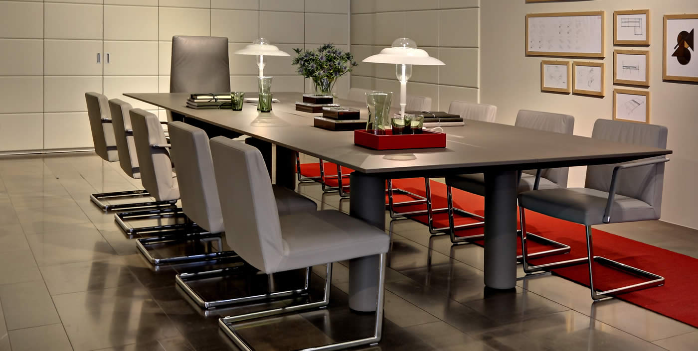 Grande table avec plateau en cuir et pieds cylindriques. Luxe et ergonomie pour vos espaces de réunion.